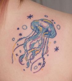 the back of a woman's shoulder with a watercolor jellyfish tattoo on it