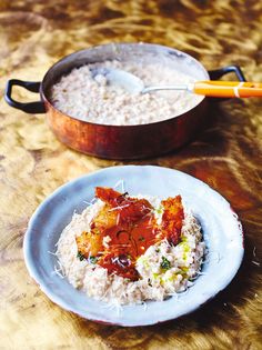 two plates with food on them sitting on a table next to a pan filled with rice