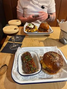 a man sitting at a table with two trays of food in front of him