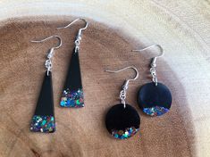 three pairs of black and blue earrings on top of a piece of wood with beads