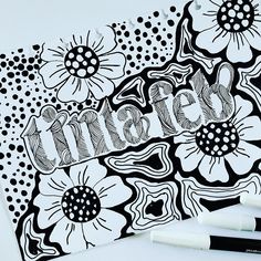 some black and white flowers are on top of a piece of paper with marker pens