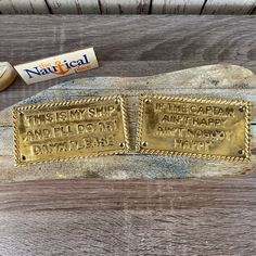 two brass plaques with writing on them sitting next to a tube of toothpaste