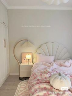 a bed with pink and white comforter in a bedroom next to a lamp on a nightstand