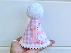 PARTY HAT: $22.95 A party hat made of stiffened felt with light pink gingham fabric, a white party goose beside, trimmed with mini white pom poms on bottom and a white yarn pom pom on the top.  Attached to a 1/8" elastic- to be worn comfortably like a headband.  Size: Small 4"x5.5" 2nd photo is example of how it fits *It's made to order so I'm HAPPY TO CUSTOMIZE TO MATCH YOUR DECOR BEST!! HIGH CHAIR BANNER: $28.00 Three 5"x5.5" scallop shape pink gingham fabric pennants, decorated with white scr Pink Gingham Party, Goose First Birthday, Goose Birthday, Hanging Cake, Gingham Party, First Birthday Hat, First Birthday Hats, Yarn Hanging, Yarn Pom Pom