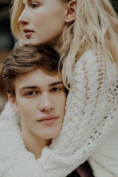 a young man and woman are posing for the camera, one is wearing a white sweater