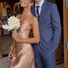 a man in a suit and tie standing next to a woman in a pink dress