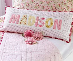 a close up of a bed with pink sheets and flowers on the pillowcases