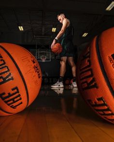 a man standing in front of three basketballs on top of a hard wood floor