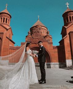 a bride and groom standing in front of a church