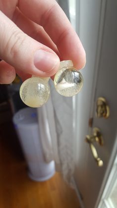 a person holding two bubbles in front of a door with the reflection of another object on it