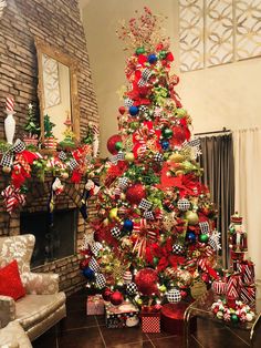 a christmas tree decorated with red, green and gold ornaments in front of a fireplace