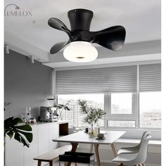 a black ceiling fan sitting above a white table in a living room next to a window