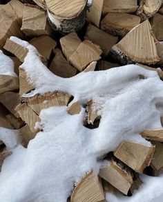 the pile of wood is covered in snow and has been cut into smaller pieces to be used as firewood