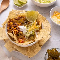 a white bowl filled with chili, beans and cheese next to tortilla chips