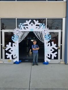 a young boy standing in front of an entrance decorated with snowflakes