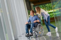 a woman pushing a man in a wheelchair