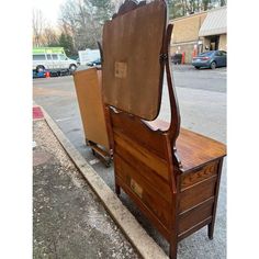 an old wooden bed sitting on the side of a road next to a parking lot