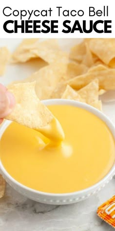 a person dipping cheese sauce into a bowl with tortilla chips on the side