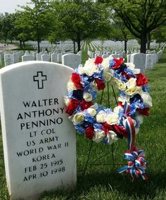 a wreath with red, white and blue flowers placed in front of a headstone