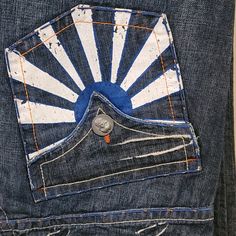 the back pocket of a pair of jeans with an embroidered sunburst on it