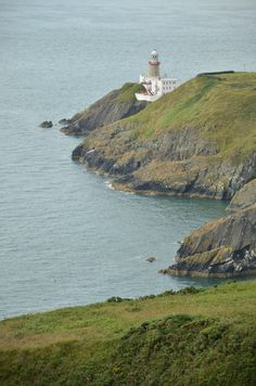 an island with a light house on it's side near the water and grass