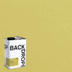 a can of paint sitting on top of a yellow wall with the words back drop