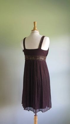 Shimmer and shine 🎆 This flapper-inspired dress features a rich brown, sheer, silk-crepe overlay with intricate copper beading; a flattering shirred, gathered bodice and jeweled straps; a floaty skirt with rows of beads accenting the pleating; and a jeweled high waist. Lined; hidden side zip. New and never worn with original store tag still attached. Fits medium sizes; pictured on a US size 6/8 dress form. Era: 1990s Label: D'Albert Fitted Brown Dress For Festive Occasions, Elegant Brown Sequin Dress, Festive Formal Brown Dress, Fitted Brown Embellished Dress, Elegant Embellished Brown Dresses, Formal Brown Embellished Dress, Flapper Inspired Dress, 1930s Gown, Colorado Girl