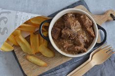 a wooden cutting board topped with meat and french fries