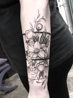 a woman's arm with flowers and leaves tattoo on the left side of her arm