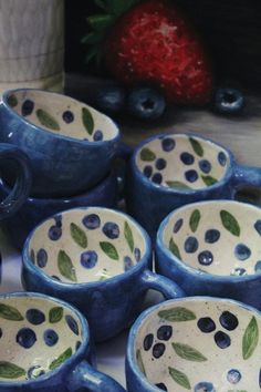 blueberries and strawberries sit in small bowls on a table next to some strawberries