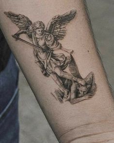 an angel tattoo on the arm of a man with a dog in front of him