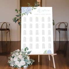 a seating chart with flowers and greenery on the floor in front of two chairs