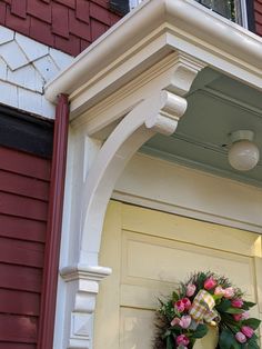 a wreath is hanging on the front door of a red brick house with white trim