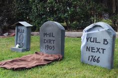 three cement headstones with the names phil, dirt next to them on grass in front of trees