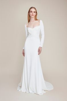 a woman in a white wedding dress with long sleeves and an asymmetrical neckline