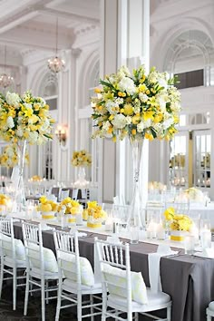 the tables are set with yellow and white flowers in tall vases on each table