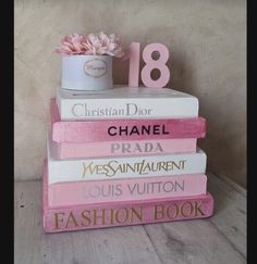 a stack of pink and white books sitting on top of each other in front of a wall