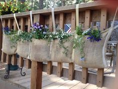 several bags filled with flowers hanging from the side of a wooden fence