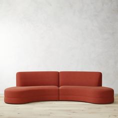 an orange couch sitting on top of a hard wood floor next to a white wall