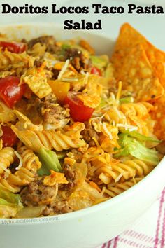 a white bowl filled with pasta and veggies next to tortilla chips