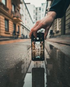 someone holding up their cell phone to take a photo in the middle of an empty street