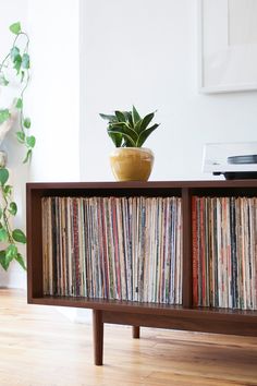 a record player sitting on top of a wooden shelf next to a potted plant