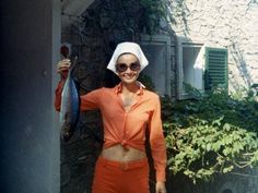 a woman in an orange outfit holding a fish