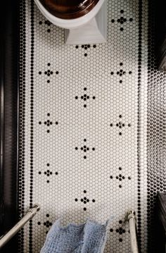 an overhead view of a bathroom with black and white tiles on the wall, toilet paper roll in the corner