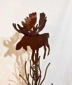 a metal moose sculpture sitting on top of a wooden table next to a white wall