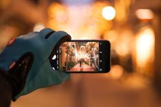 someone holding up their cell phone to take a photo in the street at night time