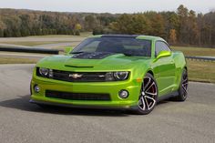 a bright green chevrolet camaro is parked on the road