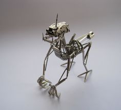 a metal sculpture of a mantisca on a white surface with gray background and grey backdrop