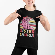 Sister Saurus Shirt, Dinosaur Sister Shirt, Sistersaurus T-Shirt, Gift for Sister, Sister Shirt, Family Dinosaur Shirt, Baby Announcement It's never too early to look great! So get your baby this short sleeve cotton jersey tee that's not only stylish, but also comfy, durable, and easy to clean. It's a classic that's bound to become the most loved item in your baby's wardrobe. * 100% cotton* * Pre-shrunk fabric * Side-seamed * Relaxed fit for extra comfort *Heather color is 52% Airlume combed and Fun Short Sleeve T-shirt With Dinosaur Print, Fun Short Sleeve Dinosaur Print T-shirt, Fun Short Sleeve Tops With Dinosaur Print, Black Dinosaur Print Short Sleeve T-shirt, Black Short Sleeve T-shirt With Dinosaur Print, Funny Dinosaur Print Short Sleeve T-shirt, Fitted Short Sleeve Dinosaur Print Top, Fitted Short Sleeve Tops With Dinosaur Print, Funny Cotton Top With Dinosaur Print