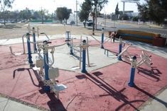 an empty playground with multiple swings and ropes on it's sides, in the middle of a city park